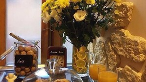 A breakfast buffet with a variety of pastries, a jar of nuts, a vase of flowers, and a glass of orange juice. - Al Ponte del Papa Bed and Breakfast (Rome)