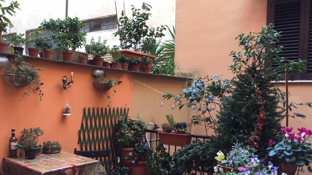A small outdoor patio with a table and chairs, surrounded by potted plants and a decorative fence. - Al Ponte del Papa Bed and Breakfast (Rome)