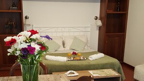 A cozy room with a bed, a dining table with chairs, a bookshelf, and a vase of flowers. - Al Ponte del Papa Bed and Breakfast (Rome)