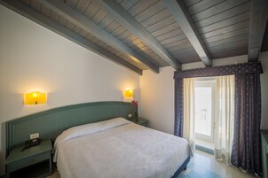 A bedroom with a bed, bedside tables, a lamp, and a window with curtains.