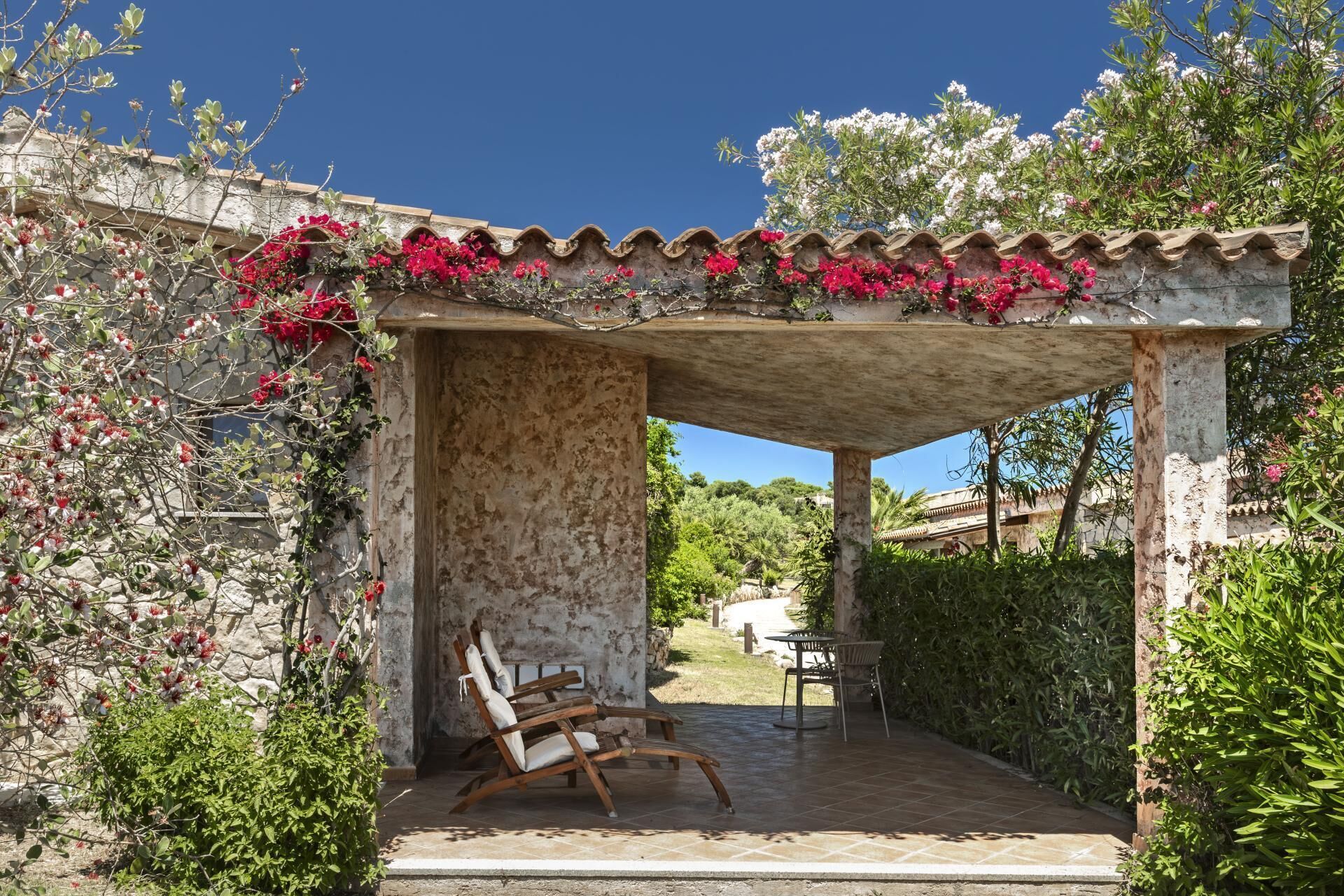 A covered outdoor seating area with stone walls, a pergola, and a view of the surrounding landscape.