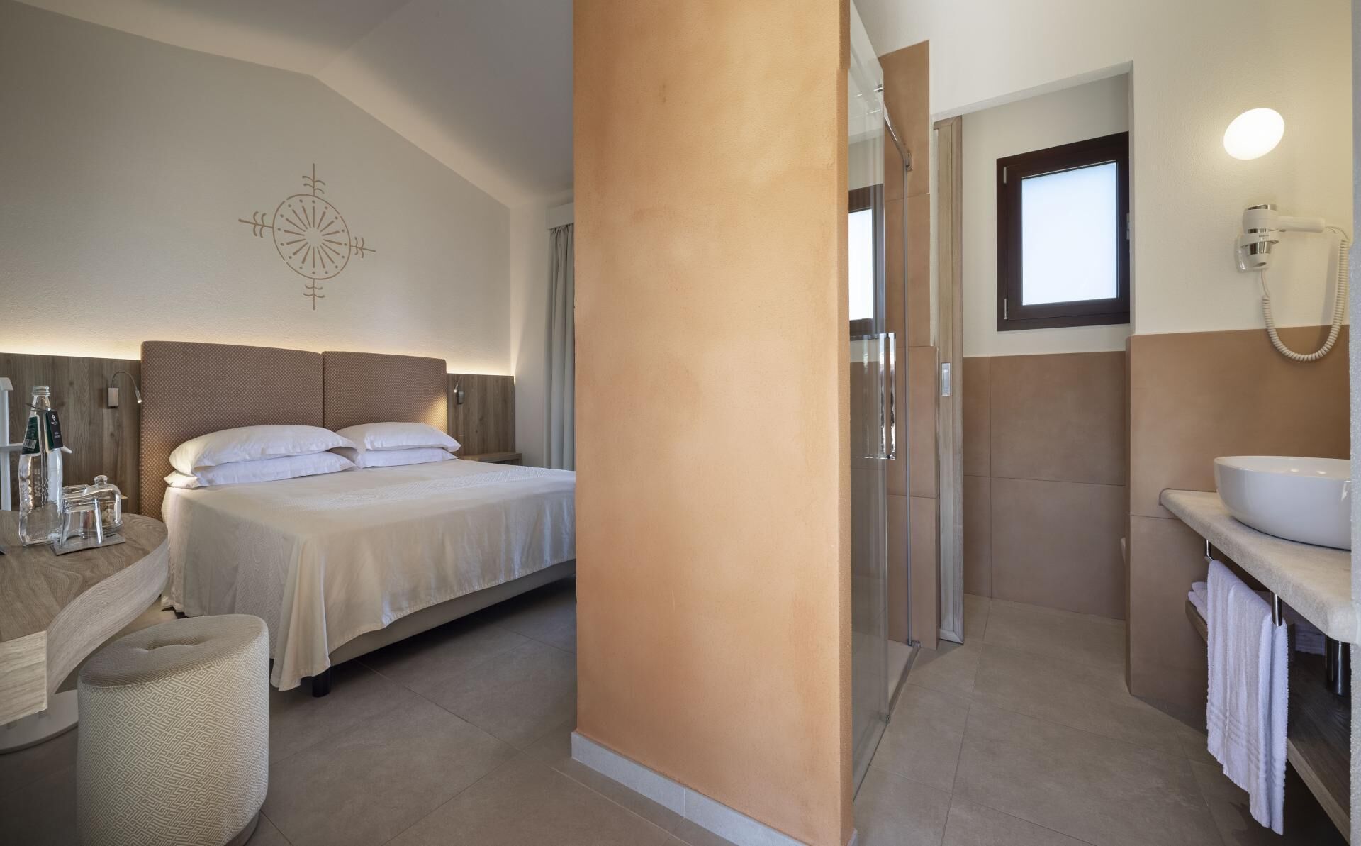 Une chambre d’hôtel avec un lit, une salle de bain comprenant un lavabo et un miroir, ainsi qu’une douche.