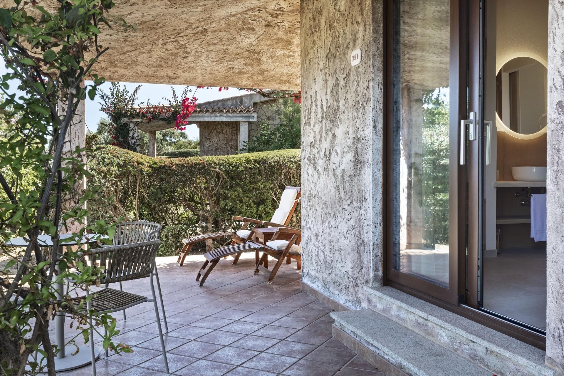 Eine Terrasse mit Sitzgelegenheiten im Freien, einer Steinmauer und Blick auf einen Garten.