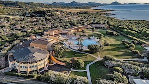 A large resort with a central pool, multiple buildings, and a view of the sea. - Sant'Elmo Beach Hotel (Castiadas)