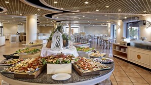 A buffet setup with various food items, a large white lantern, and a modern ceiling design. - Sant'Elmo Beach Hotel (Castiadas)