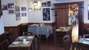 Un restaurante con varias mesas dispuestas para comer, cuadros en las paredes y un televisor colocado sobre las mesas.