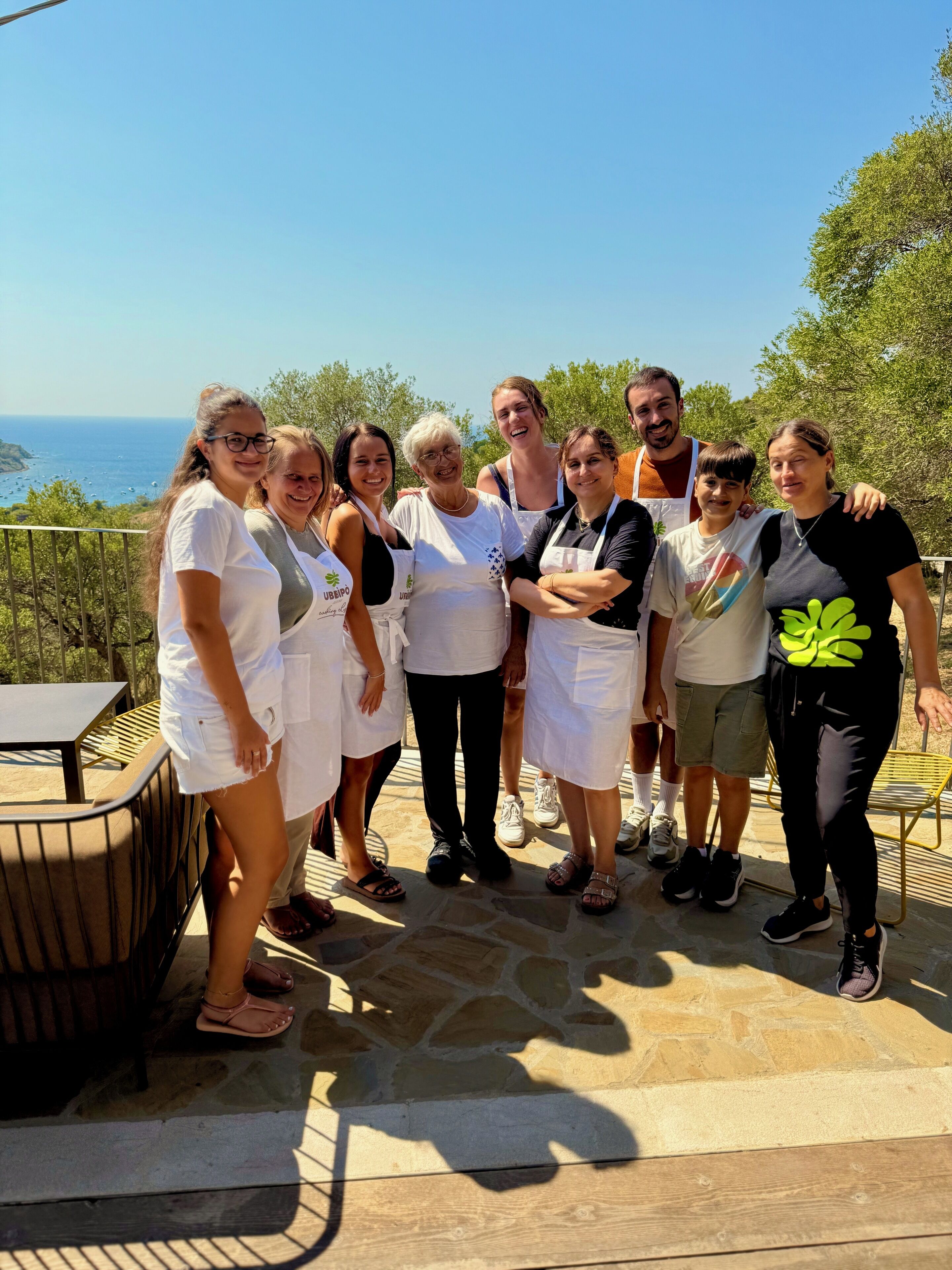 A group of people standing on a terrace with a view of the sea.