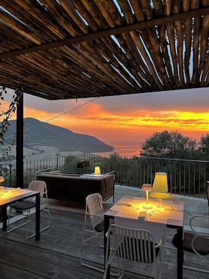 An outdoor patio with tables and chairs, a pergola overhead, and a scenic view of a sunset over a valley. - Baia Di Trentova (Agropoli)