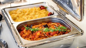 A buffet with macaroni and cheese and a vegetable dish garnished with greens.