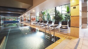 A swimming pool with lounge chairs, a lifeguard chair, and a view of the outdoors.