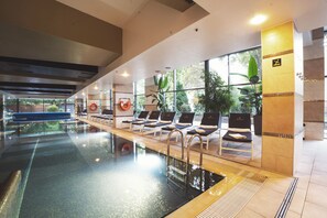 A swimming pool with lounge chairs, a lifeguard chair, and a view of the outdoors.