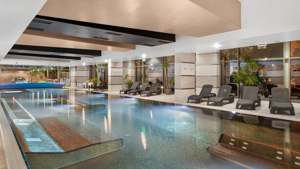 An indoor swimming pool with lounge chairs and potted plants.
