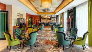 A bar area with green upholstered chairs and a bar counter.