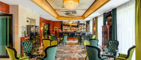 A bar area with green upholstered chairs and a bar counter.