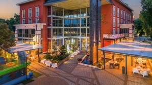 A hotel with a modern glass facade, outdoor seating area, and a rooftop terrace.
