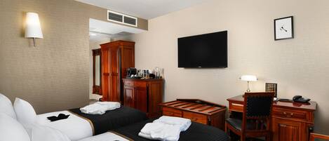 Habitación de hotel con dos camas, un escritorio, una silla, un televisor y una lámpara.