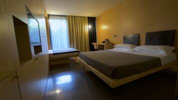 Una habitación de hotel moderna con una cama grande, un escritorio y una silla.