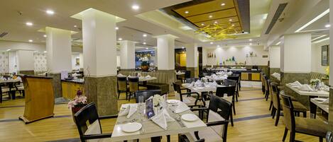 Un restaurant spacieux, doté de nombreuses tables et chaises, d’un comptoir et d’un plafond décoratif.