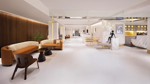 Un hall d’hôtel moderne comprenant un comptoir d’accueil, un espace salon et une statue.