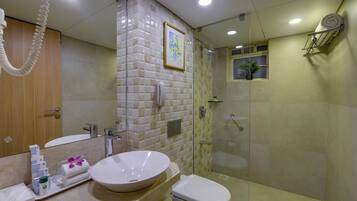 Un baño moderno con un espejo grande, un lavabo blanco, un inodoro y una ducha con mampara de cristal.