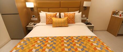 A hotel room with a large bed, a bedside table with a lamp, and a nightstand with a phone.