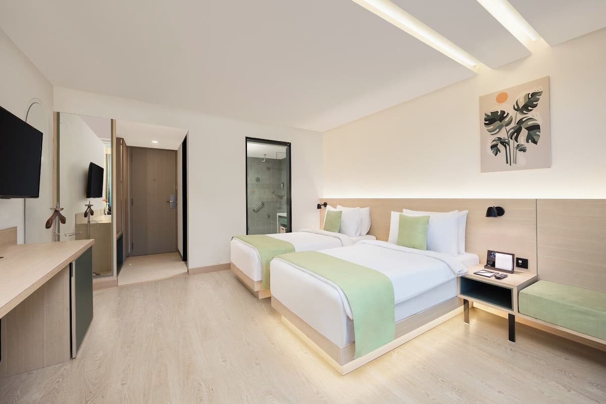 Une chambre d’hôtel moderne équipée de deux lits, d’un bureau, d’une télévision et d’un espace douche.