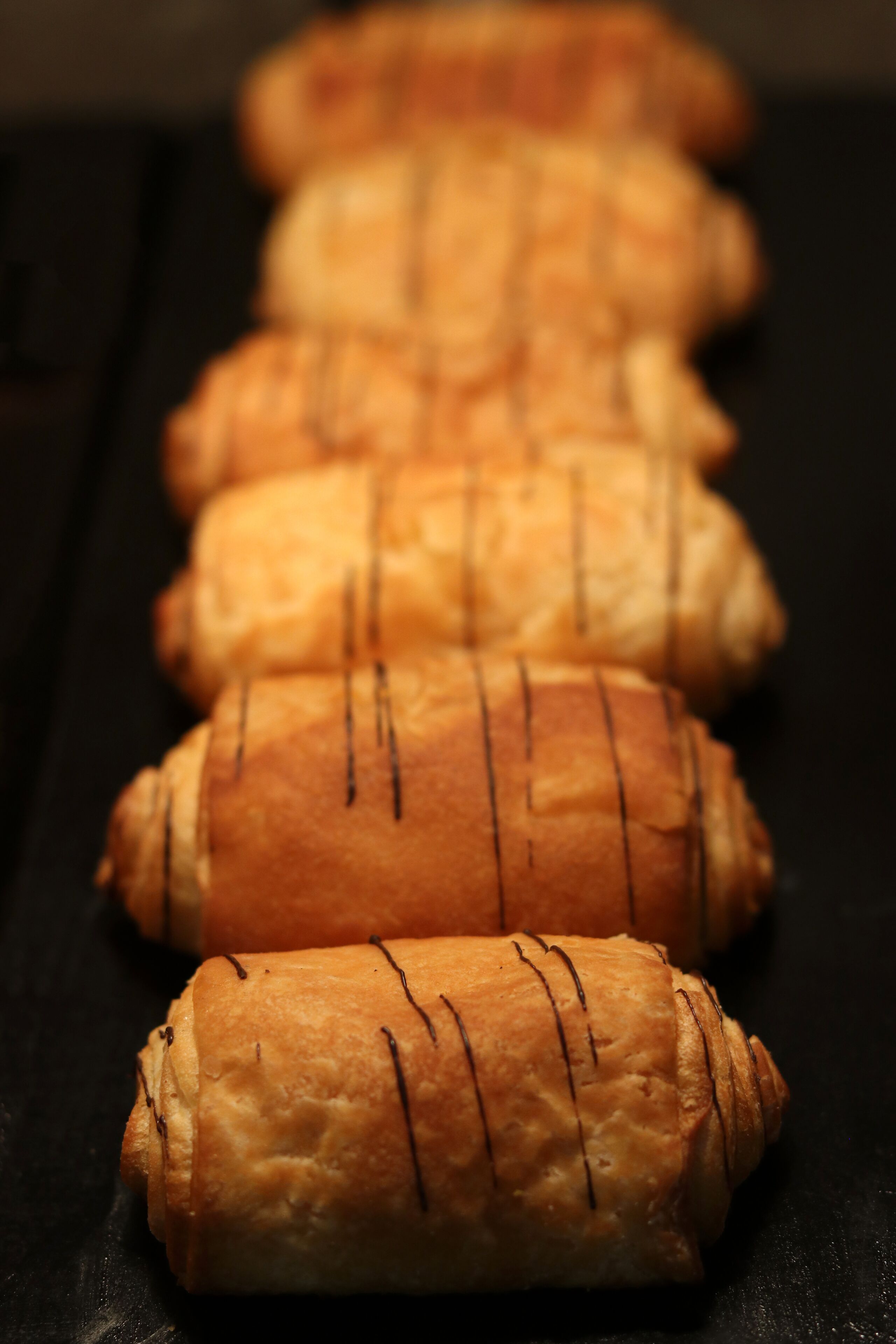Une rangée de pâtisseries sur une surface sombre.