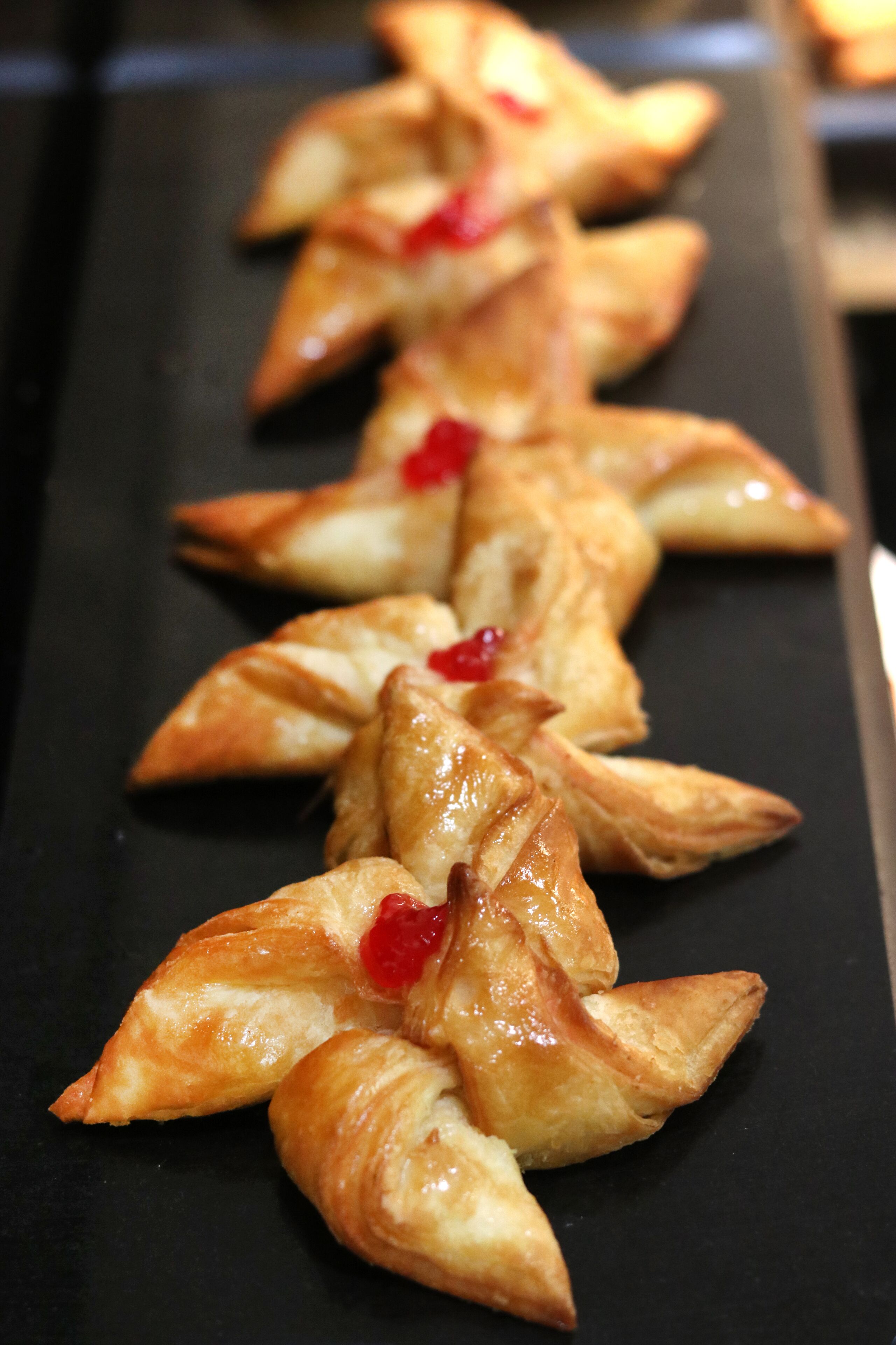 A row of pastries on a black tray.