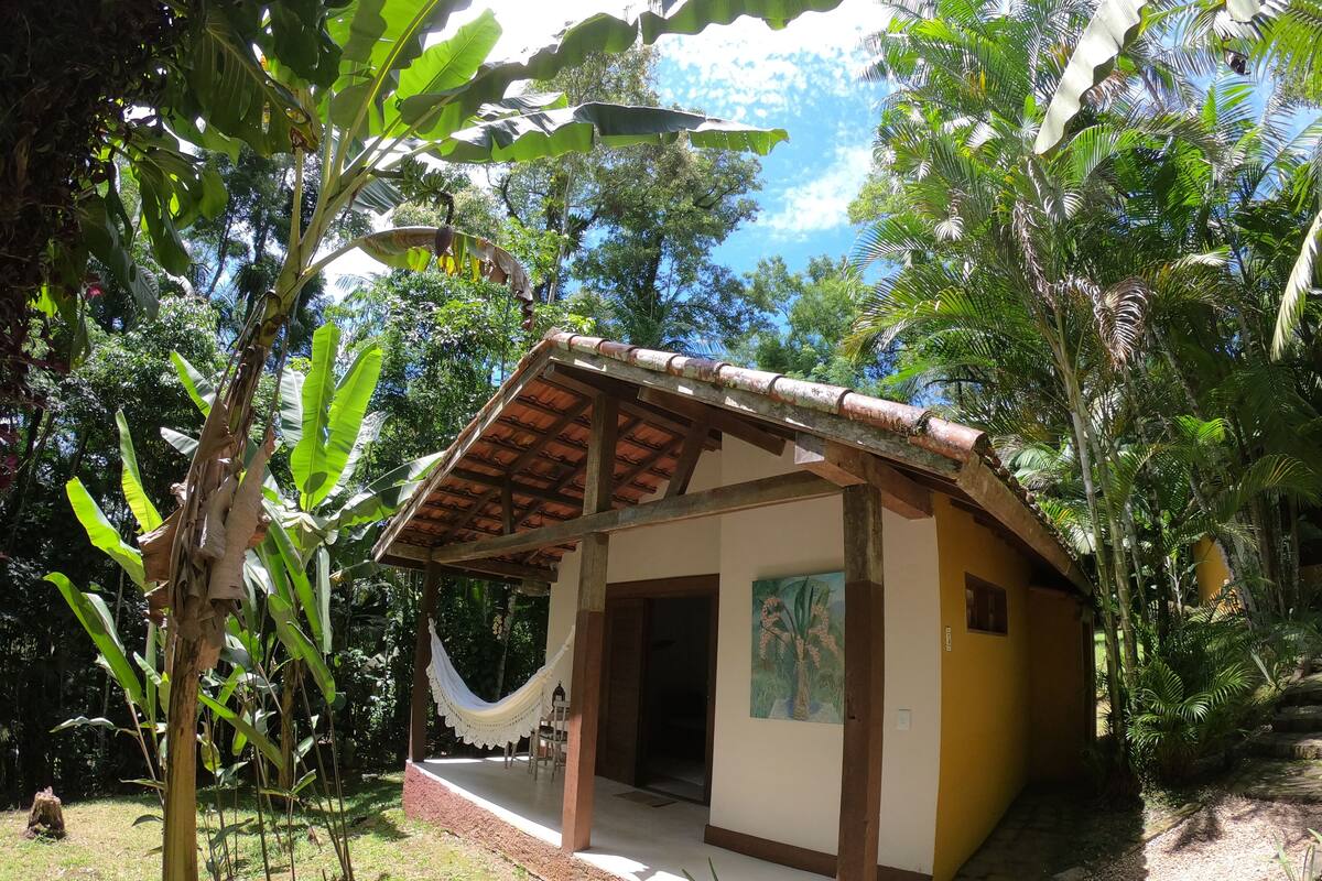 A small, single-story building with a tiled roof, surrounded by lush greenery and trees.