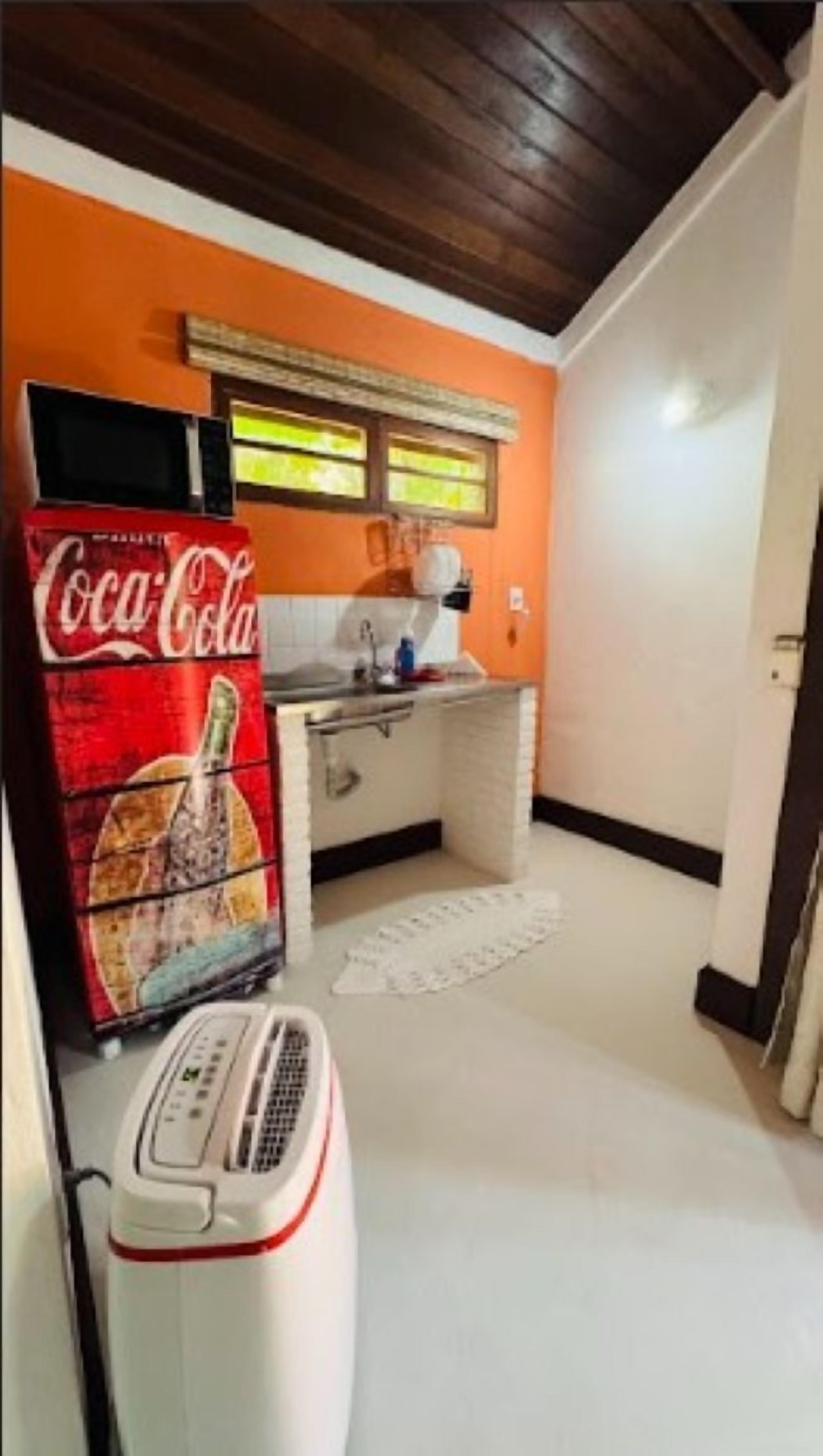 A compact kitchen with a microwave, a Coca-Cola refrigerator, and a small sink.
