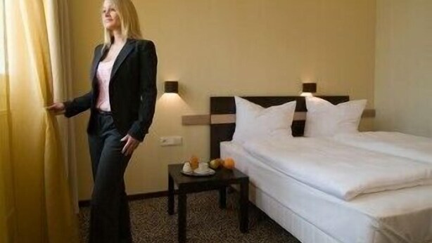 Ein Hotelzimmer mit einem Bett, einem kleinen Tisch mit Obstschale und einem Vorhang.