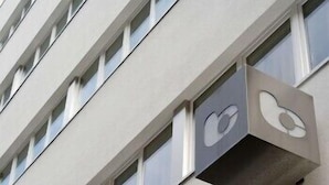 Eine auffällige Gebäudefassade mit einem markanten Logo an der Ecke, mehreren Fenstern und einem flachen Dach.
