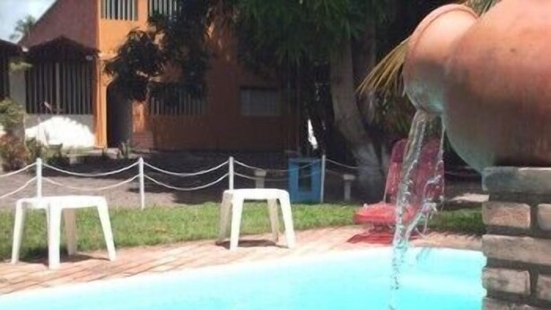 A swimming pool with two white chairs and a water fountain.