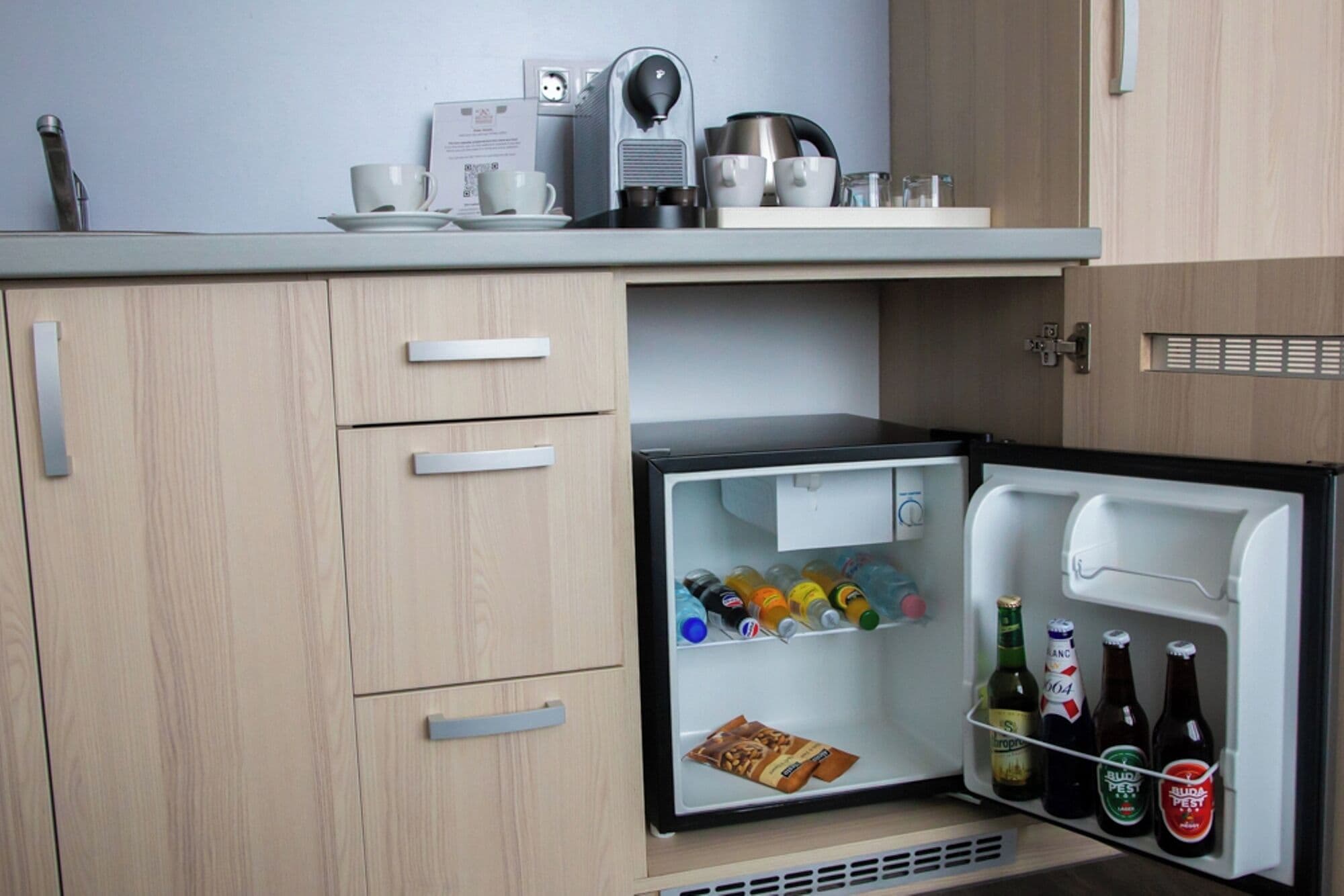 Une cuisine compacte dotée d’un réfrigérateur intégré contenant des boissons et des en-cas.