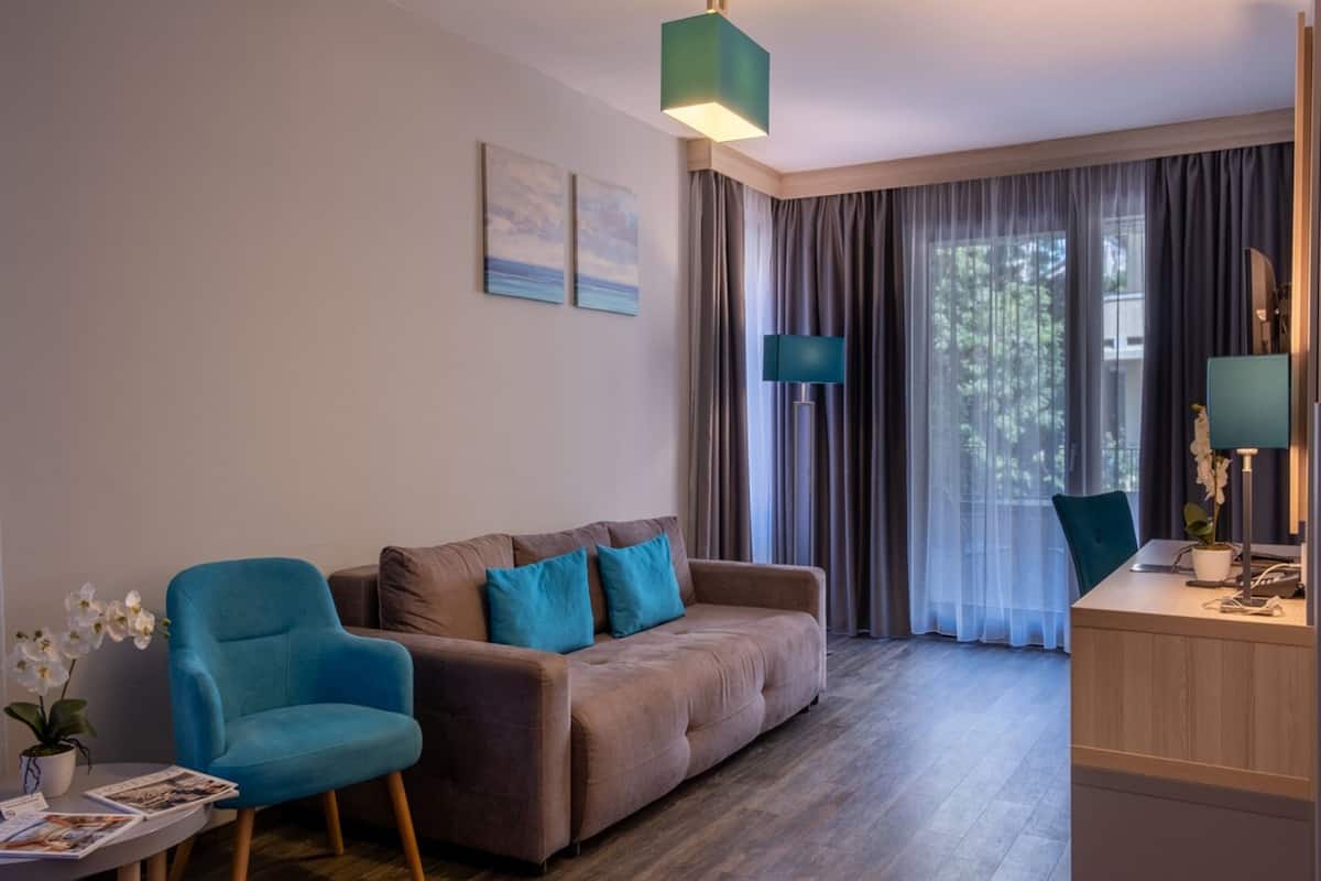 A modern living room with a sofa, a blue armchair, a wooden desk, and a lamp.