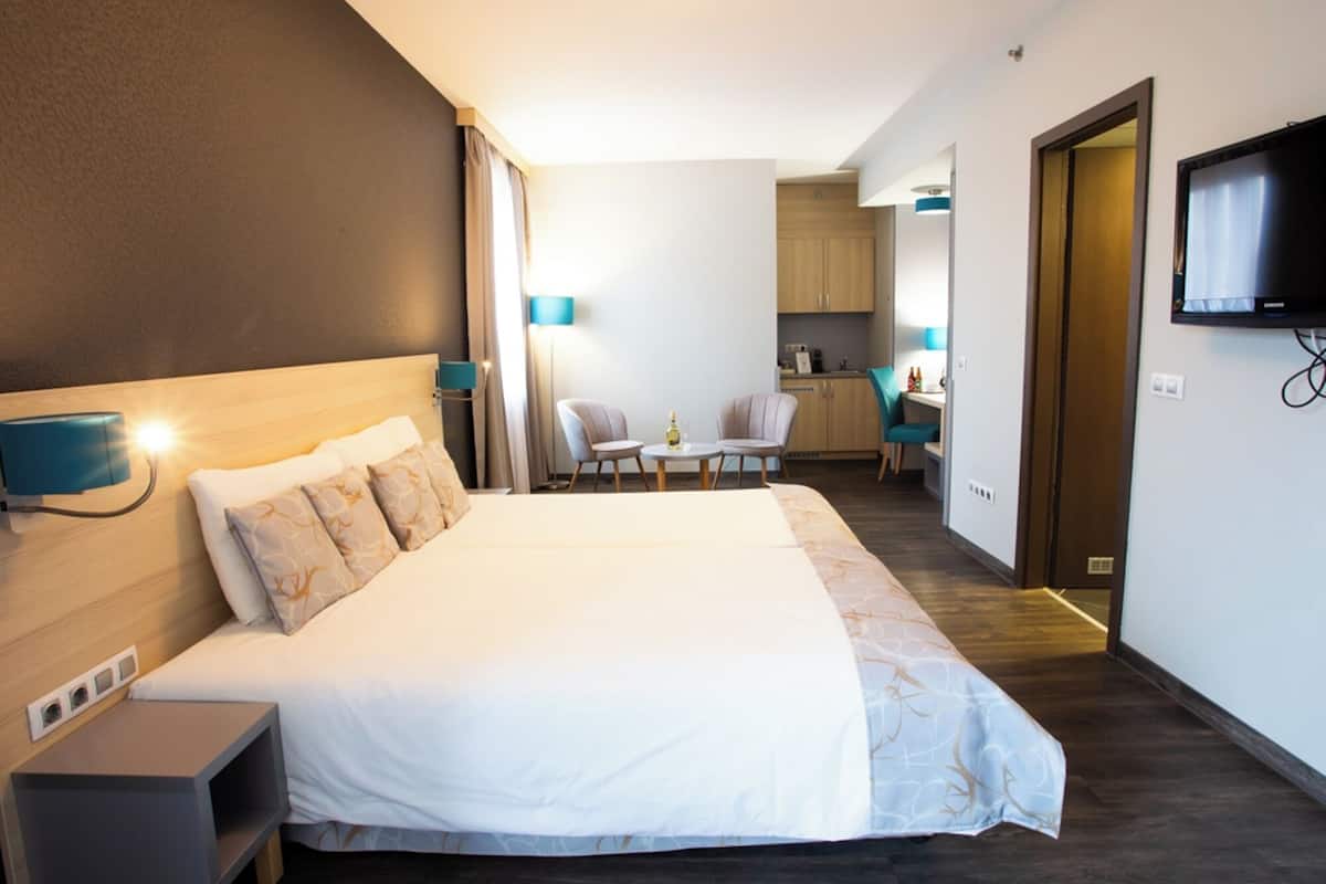 A hotel room with a bed, bedside table, and a TV mounted on the wall.