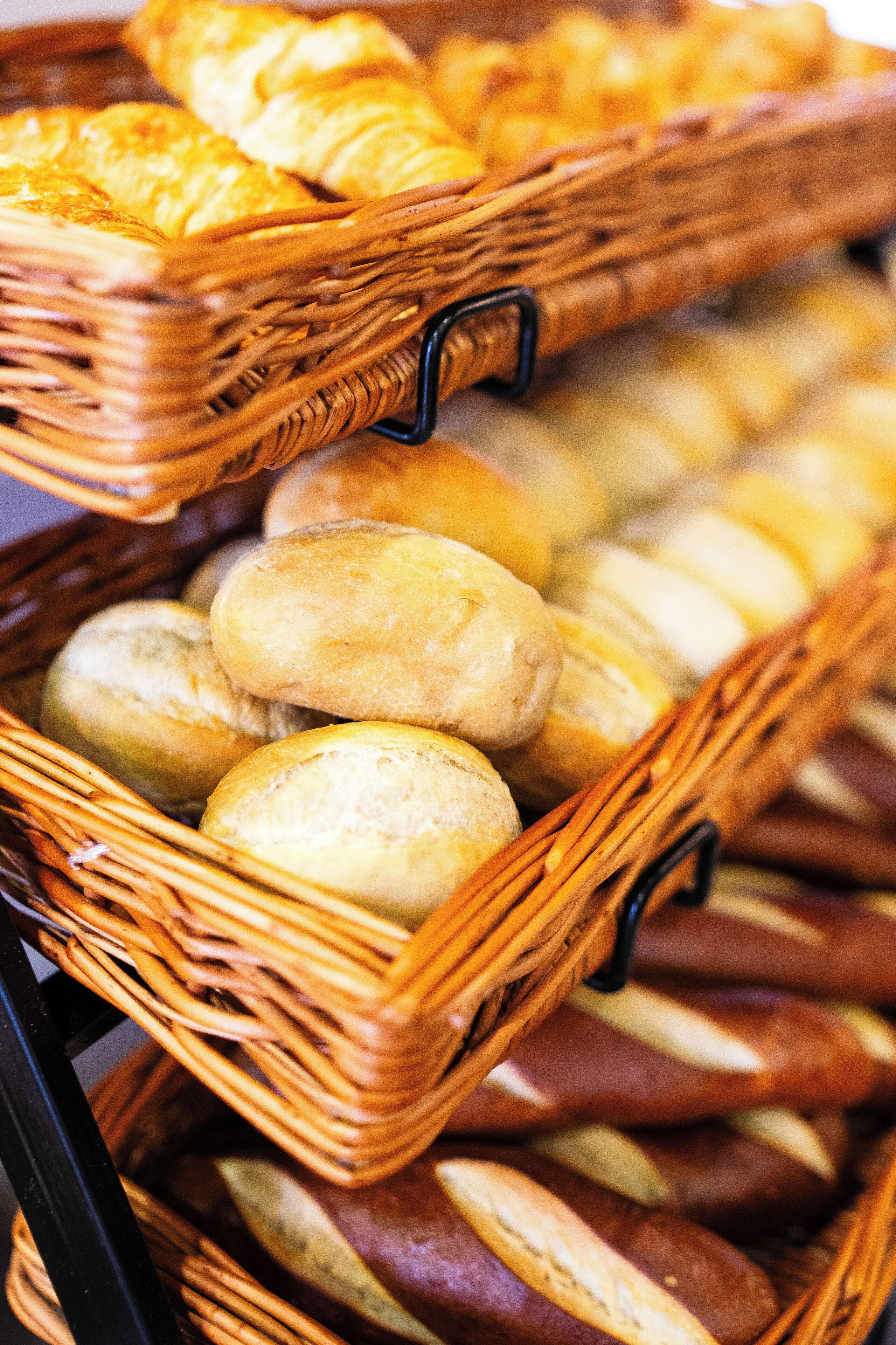 A display of various breads in wicker baskets.