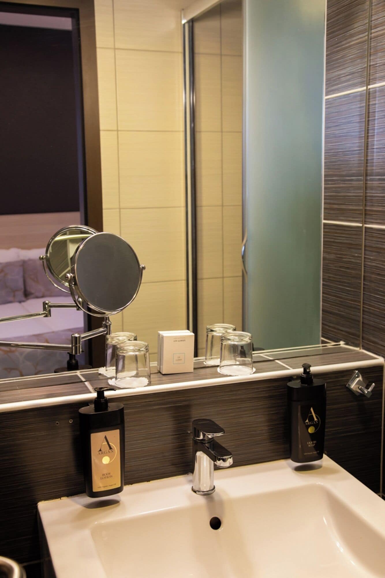A bathroom with a large mirror, a sink, and a vanity.