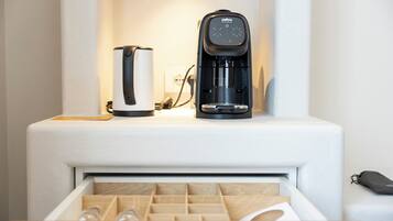 Una cocina moderna con cafetera y hervidor sobre una encimera blanca.