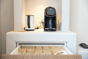Ett modernt kök med en kaffebryggare och en vattenkokare på en vit bänkskiva.