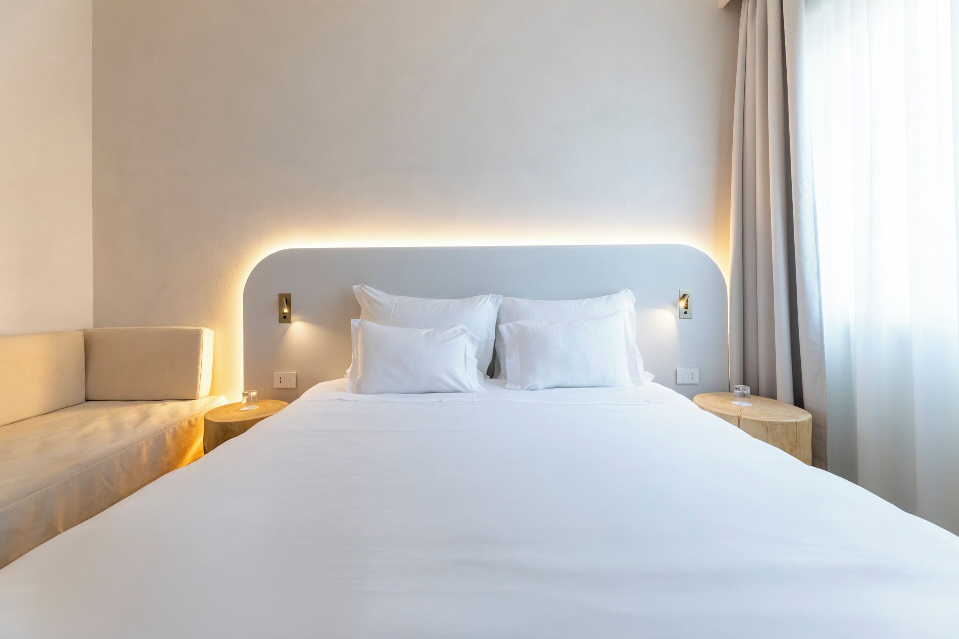 A hotel room with a large bed, two bedside tables, a chair, and a nightstand.