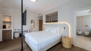 Ein modernes Hotelzimmer mit einem großen Bett, einem kleinen Schreibtisch, einem Spiegel und einem Badezimmer mit Duschwc.