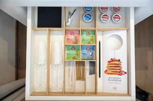 Un minibar d'albergo con articoli da toilette assortiti e una foto incorniciata di pancakes.