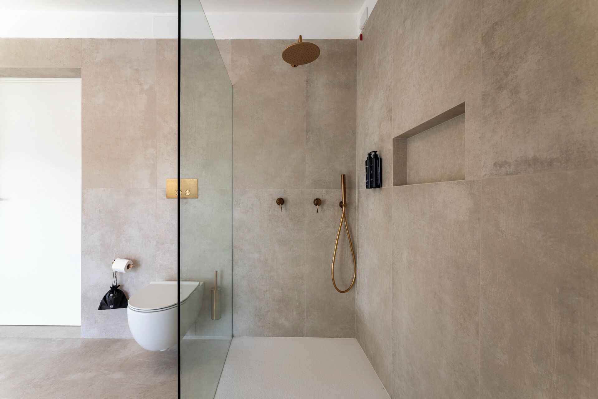 A modern bathroom with a glass shower enclosure, a toilet, and a sink.