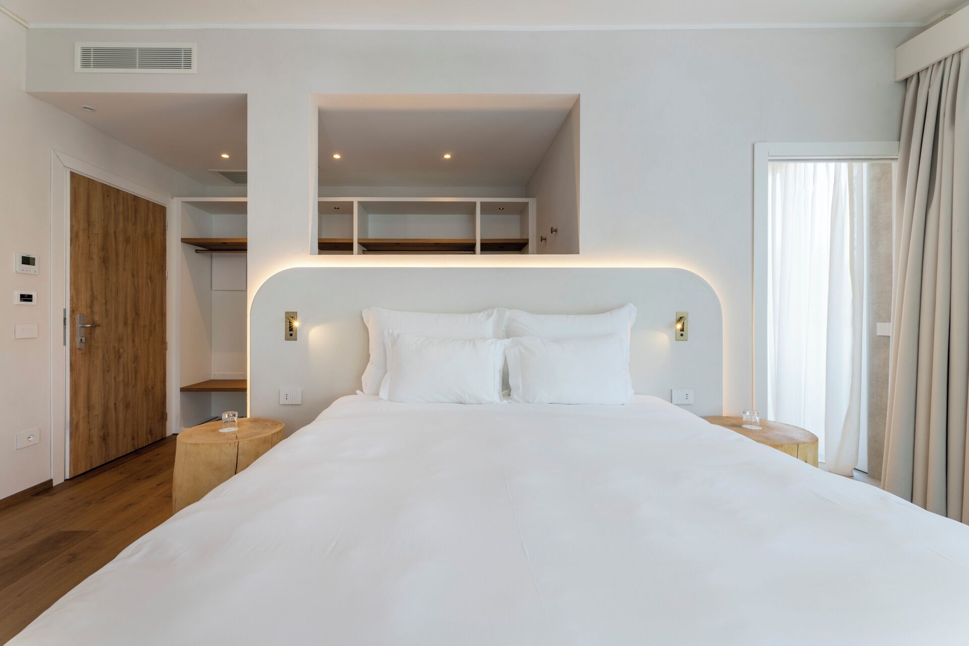 Une chambre moderne avec un grand lit, des étagères intégrées et une vue sur l’extérieur.