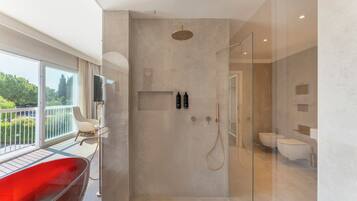 Une salle de bain moderne avec une douche à l’italienne en verre, un lavabo blanc et une baignoire rouge.