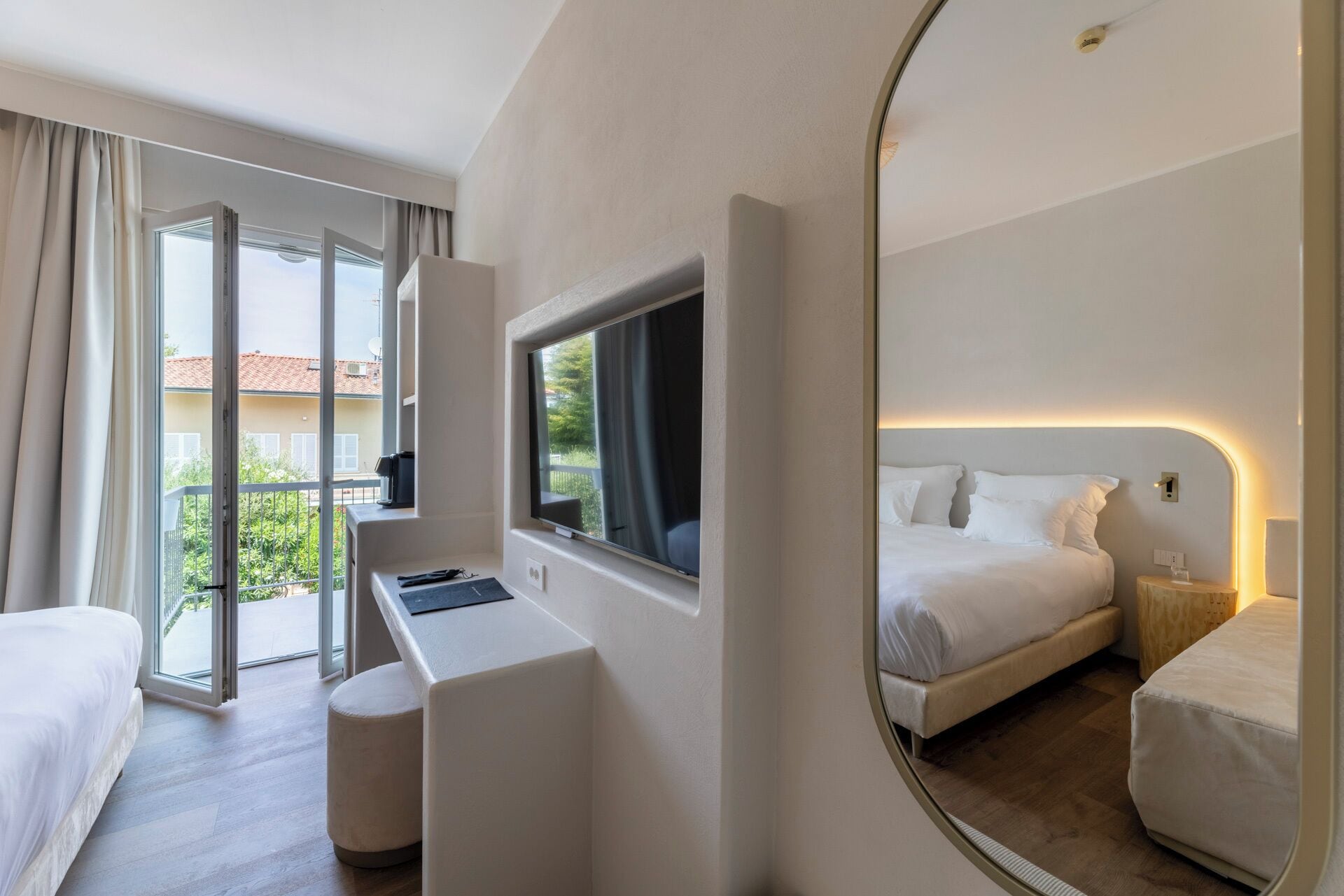 Ein Hotelzimmer mit einem Bett, einem Schreibtisch, einem Fernseher und einem großen Spiegel.