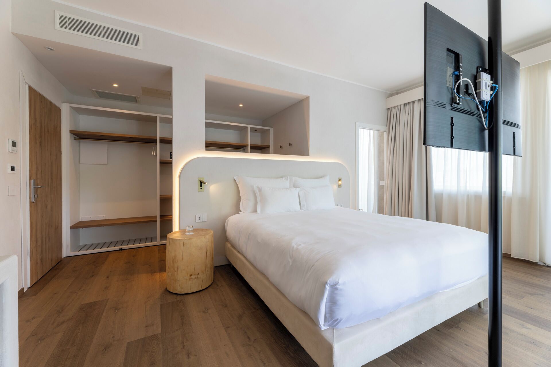 Une chambre d’hôtel moderne dotée d’un grand lit, d’une armoire intégrée et d’un téléviseur à écran plat.