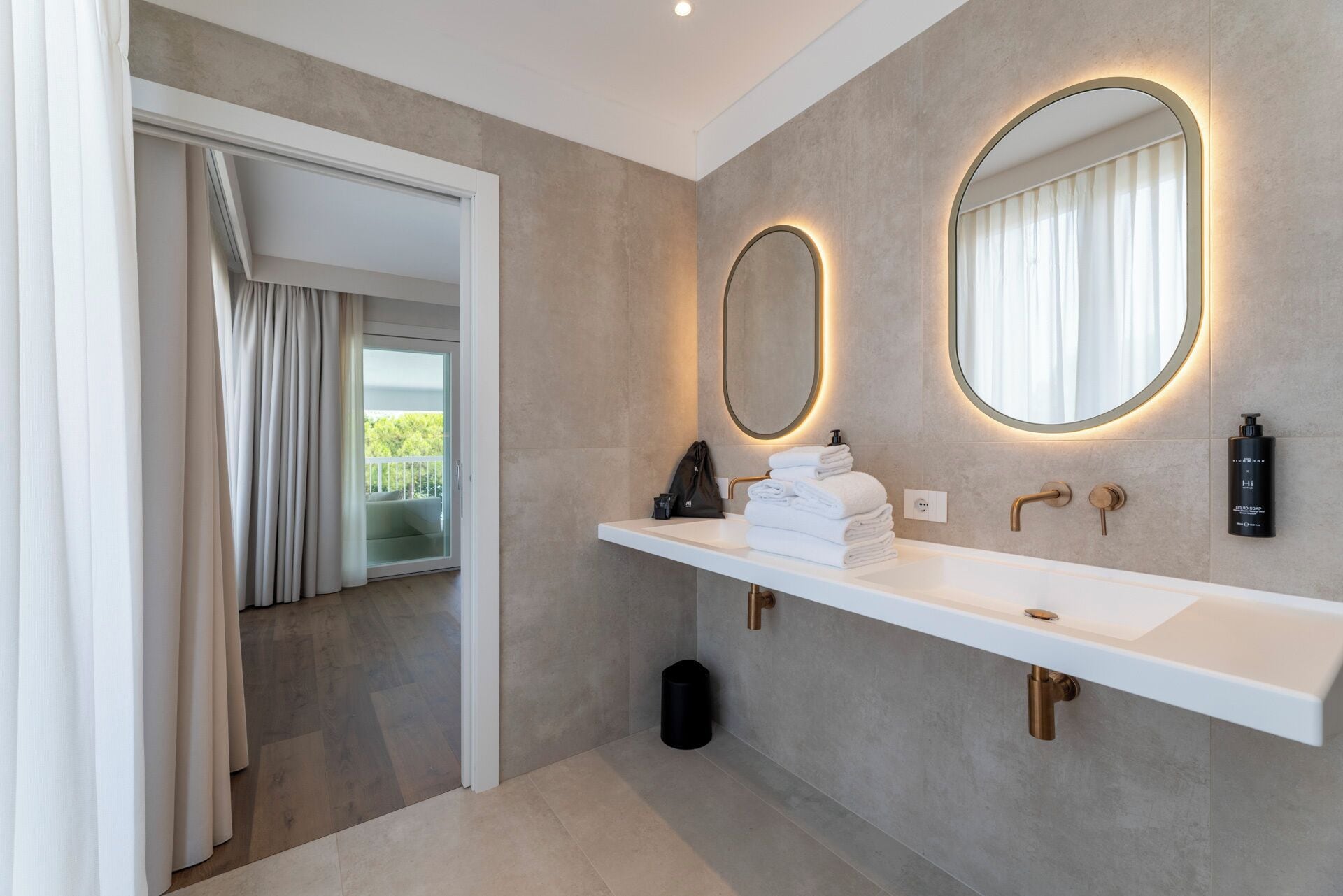 Un bagno moderno con un grande specchio, un lavandino bianco e un portasciugamani.