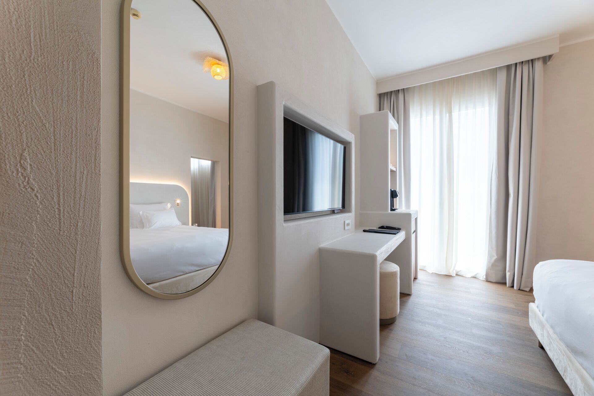 Une chambre d’hôtel moderne dotée d’un grand miroir, d’un téléviseur à écran plat, d’un bureau et d’un lit confortable.